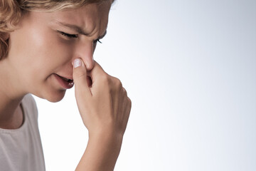 Strong disgust smell bad breath of young woman. Close-up portrait of a girl covering close her nose by fingers, expression face disgusting, dislike odor