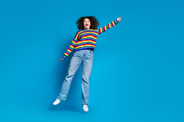 Full length photo of lovely young lady hanging jump flying wear trendy rainbow print garment isolated on blue color background