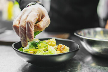 Chef cooking Caesar salad on restaurant kitchen
