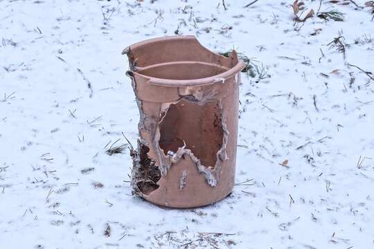 one old brown broken and melted plastic bucket with a hole standing on white snow on a winter street