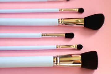Various different make up brushes on pink background. Selective focus.