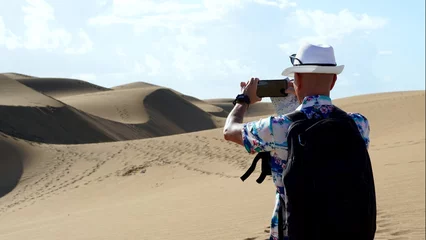 Photo sur Aluminium les îles Canaries Half-figure tourist photographing the curves of the sand dunes with the phone