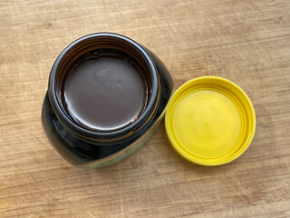 Open jar of marmite yeast extract spread, british speciality, on wooden chopping board. Love it or hate it