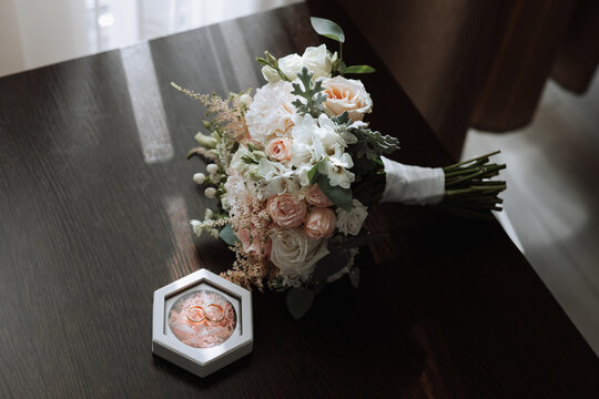 On the floor are men's dark leather shoes and a black belt, a man's suit on a mannequin, a wedding bouquet of flowers, wedding rings, men's perfume. Photo, top view.