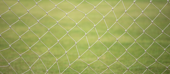 Soccer goal net on green grass field, sport background texture.