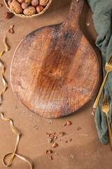 Cutting board on a kitchen table with Christmas decoration, nuts and christmas festive decorations. Top view, winter holiday mockup concept composition.