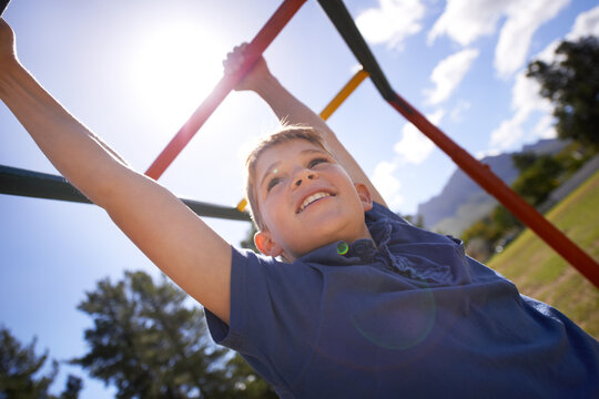 Child, monkey bars and energy on playground, smiling and obstacle course on outdoor adventure at park. Happy male person, active and exercise on jungle gym, boy and fitness on vacation or holiday