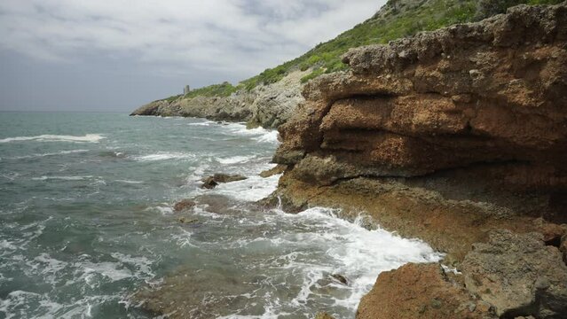 Rocks in the sea of SpRocks in the sea of Spain at a strong wind. White splashing waves crash against the shore. Rocks in the sea of Spain at a strong wind. White splashing waves cain at a strong wind