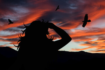 Silhouette of a woman looking at the landscape at sunset. Nature and people.