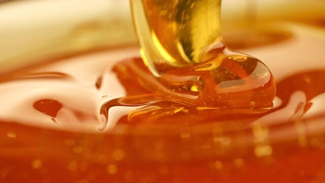 Scoop honey with a spoon. Golden thick honey dripping from spoon close up