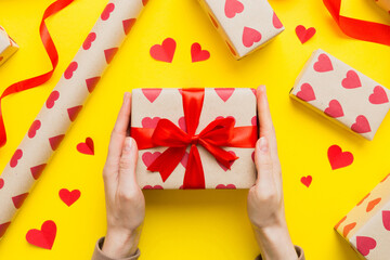 Give a gift on Valentine Day.Valentine gift. Beauty Woman hands holding Gift box with red bow over holiday background