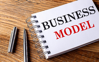 BUSINESS MODEL text on notebook with pen on wooden background