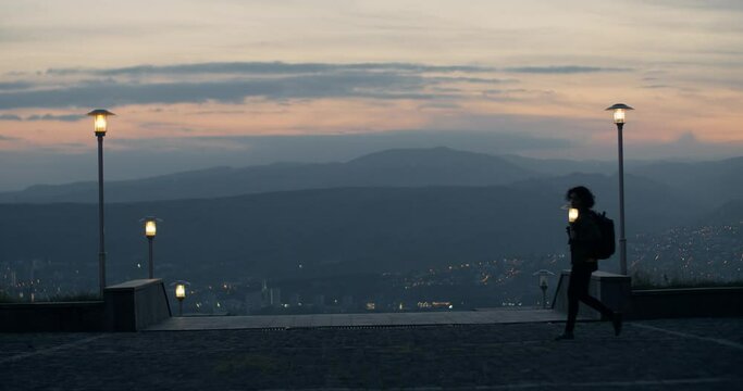 Girl walking by stunning evening city landscape