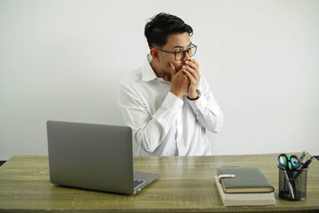 young asian businessman in a workplace covering mouth and looking to the side, wearing white shirt with glasses isolated