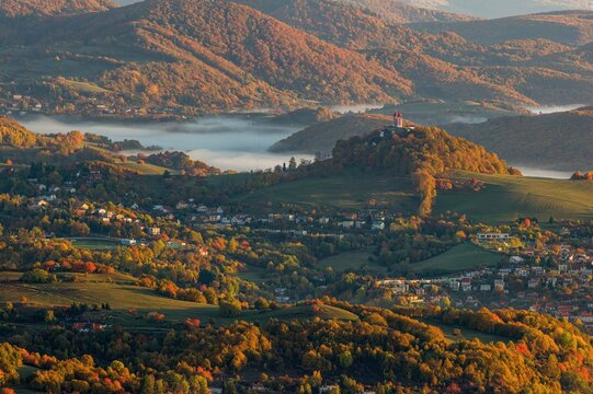 Beautiful autumn landscape of a church on a hill,  autumn fog in the valleys. Idyllic scenery from a bird's eye view of the picturesque town of Banska Stiavnica