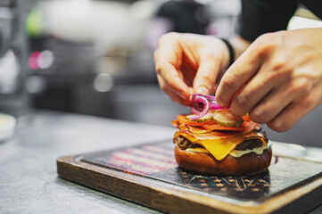 chef hand cooking cheese burger on restaurant kitchen