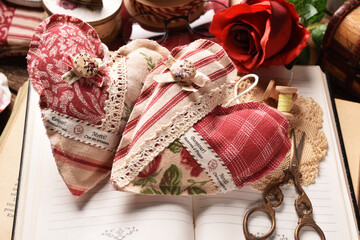 Vintage style still life with two handicraft textile hearts lying on opened books