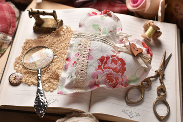 Vintage style still life with handicraft textile heart lying on opened books top view