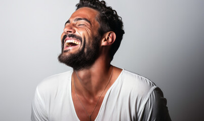 Fototapeta premium Vibrant Portrait of a Joyful Middle-Eastern Man Laughing with Eyes Closed, Wearing a White Shirt on a Plain Background