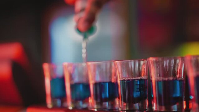 Barman prepares party shots in nightclub closeup. Barkeeper makes shooter sets pouring alcoholic drinks for party guests. Hard drink for celebrations