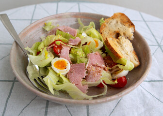plate with salad with ham and quail eggs on the table