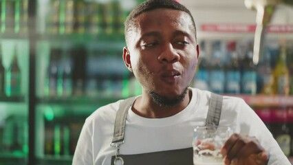 Black man degustates beer with satisfaction in pub closeup. African American brewer checkups taste of light alcohol drink working in bar. Craft brewery owner - Powered by Adobe