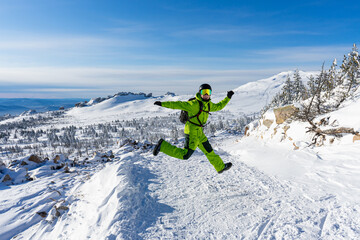 Happy Man jumping Bright acid green outfit: warm suit, goggles, black helmet, gloves, backpack....