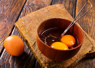 Bowl with raw egg yolk on wooden table, closeup - 720307794