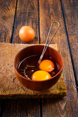 Bowl with raw egg yolk on wooden table, closeup - 720307796