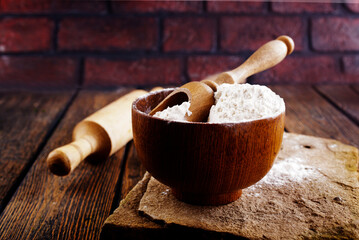 Overhead view of bowl with flour placed on messy wooden table in kitchen of bakehouse - 720307979
