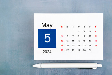 May Calendar 2024 page with pen on wooden background.