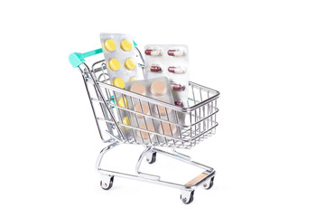 Medical shopping concept: shopping cart with pills on white background