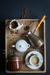 Cup of coffee, milk jug, coffee grinder, coffee quark and coffee beans in a bag on a dark...