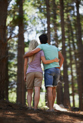 Naklejka na ściany i meble Couple, walking and hug in forest for love, embrace or support in trust, care or bonding in nature. Rear view or back of young man and woman in romance, affection or hiking together in outdoor woods