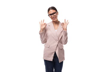 Naklejka premium pretty smart young woman with black hair and glasses for vision is dressed in a beige jacket and jeans on a white background