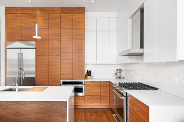 A kitchen detail with white and wood modern cabinets, a white hexagon tile backsplash, stainless...