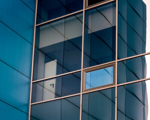 mirrored windows of the facade of an office building with blue panels and yellow window frames