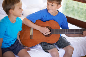 Children, music and siblings on a bed with guitar for playing, bonding or learning together in...