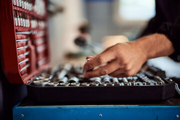 A mechanic putting a tool into his tool case, working at the repair shop.