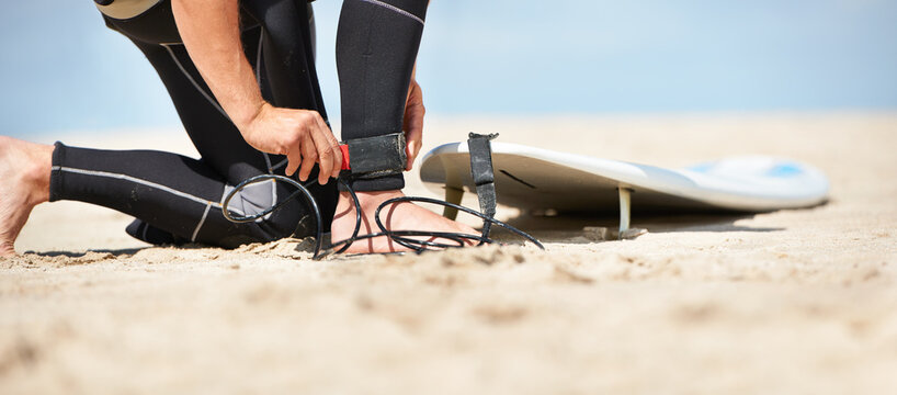 Legs, strap for safety and surfer on beach for sports, fitness and training on travel vacation in summer. Hands, ankle and surfboard with person on sand by ocean or sea for surfing hobby or holiday - Powered by Adobe