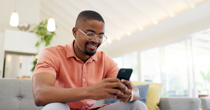 Happy, typing and a black man with a phone on the sofa for social media, connection or communication. Smile, relax and an African person with a mobile for an app, email or notification in a house - Powered by Adobe