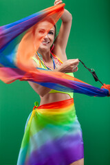 Brazilian woman isolated on a green background dancing with a colorful shawl
