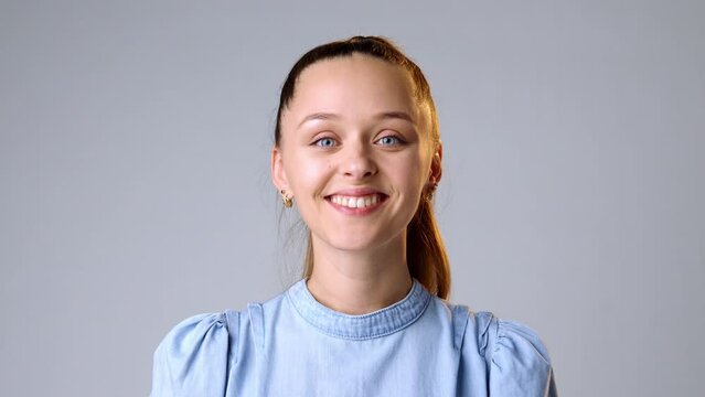 Young woman smiling and laughing at a joke against gray background