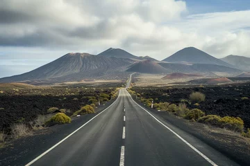 Poster Image related to unexplored road journeys and adventures.Road through the scenic landscape to the destination in Lanzarote natural park © Amer