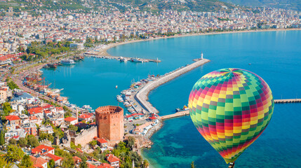 Obraz premium Hot air balloon flying over marina and Red Tower (Kizil Kule) in Alanya peninsula - Antalya, Turkey