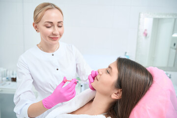 Fototapeta premium Beautician making beauty procedure to young woman