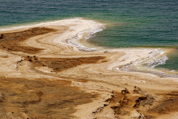Shore of Dead Sea of Jordan side. Emerald water of  Dead Sea leaves, exposing stepped sandy coast. Traces of dying sea. Spring 2011. Ecology theme.
