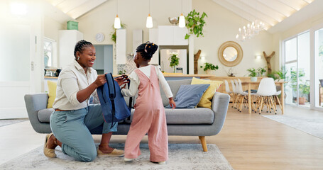 Talking, happy and a mother with a child getting ready for school in the morning. Kiss, laughing and an African mom helping a little girl with a bag in the living room of a house for kindergarten