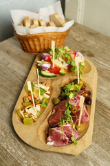 Selection of prosciutto, local cheese, chorizo sausage and vegetables on a wooden plate