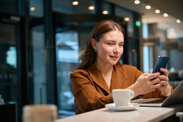 Lady sitting at counter and typing something on smartphone